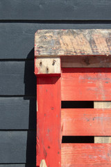 Orange pallett leaning against a black wooden shed