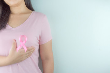 Healthcare, medicine and breast cancer awareness concept. Closeup on woman chest with pink breast cancer awareness ribbon.