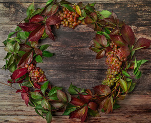 Beautiful wreath frame with grapes, leaves and vine on wooden boards. Flat lay style. Fall concept.
