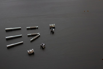 screwdriver and screws for assembling furniture on a black wooden background