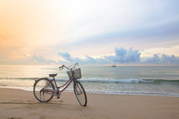 Fototapeta premium classic bike park on sand beach with sea in cloundy sun rise morning