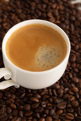 white cup with black coffee and coffee beans close-up