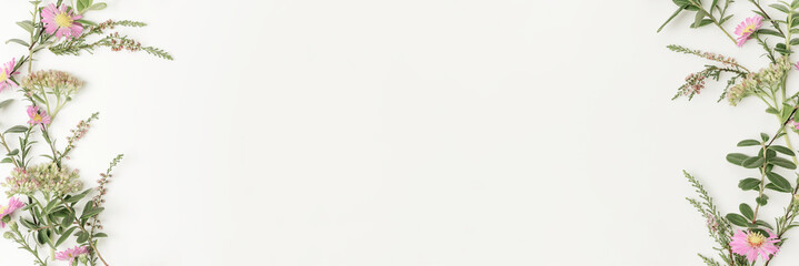 Beautiful and tender web banner with pink daisies, branches, leaves and petals on white background. Flat lay style. Overhead view. Copy space.