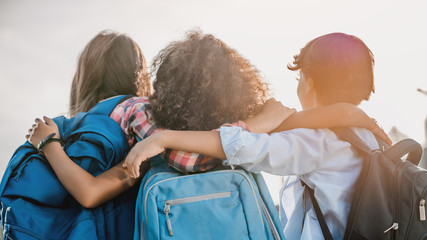 Rear view of school childrens that hugging each other outdoors