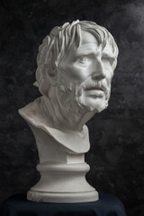 Gypsum copy of ancient statue Seneca head on dark textured background. Plaster sculpture man face.