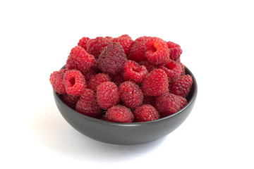 Fresh raspberries in dark bowl isolated on white background