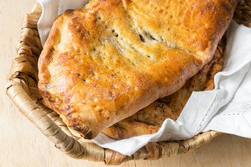 Delicious home baked apple and raisins turnover slab pie with cinnamon and nutmeg filling in wicker basket on rustic wooden kitchen table. Autumn dessert recipe holiday treat