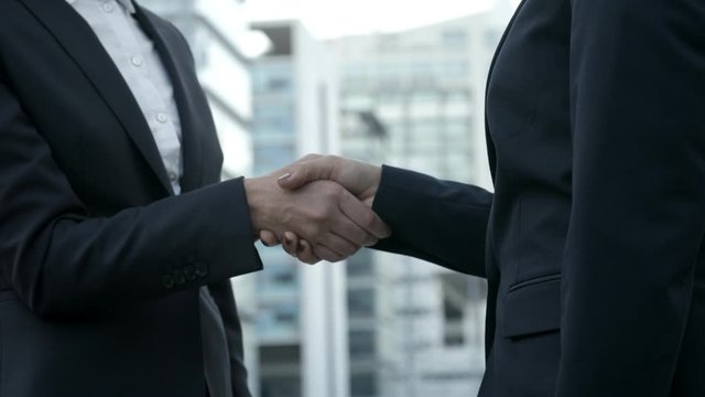 Side view of businesswomen shaking hands on street. Colleagues meeting on street and making handshake. Business handshake concept