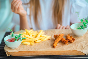 Closeup crispy potato fries with two dipping sauce and fresh chicken fingers served on Rustic...