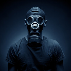 Young man in a gas mask against a dark background