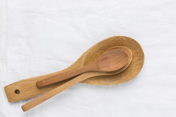 Wooden cooking spoons of different sizes on pure cotton linen table cloth. Culinary baking utensils artisan craftsmanship products natural material concept