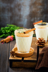 Eggnog Traditional Christmas drink milkshake with cinnamon on dark old background. Selective focus.