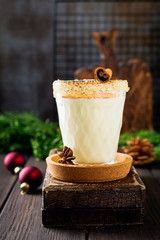 Eggnog Traditional Christmas drink milkshake with cinnamon on dark old background. Selective focus.