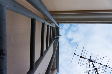 Staircase leading to a rooftop of a building. Gray metal stairways leading to the roof with visible antenna and beautiful sky.