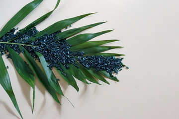 Multitude of green blue tubular toho beads and green leaf .