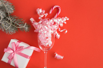 Christmas composition with a champagne glass and gift on the red background. Copy space. Top view.