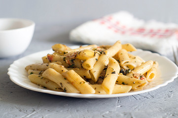 Pasta with pesto in a white bowl on a gray stone background.