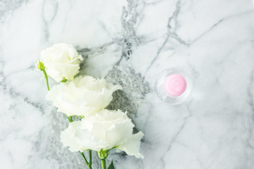 Obraz na płótnie Canvas Pink transparent spray bottle and flowers on marble. Flat lay. Natural products for cleaning or body care concept