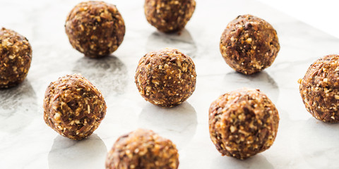 Energy protein balls with healthy ingredients on marble table. Home made with dates, peanut butter,...