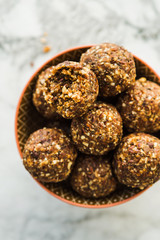 Energy protein balls with healthy ingredients on marble table. Home made with dates, peanut butter, flax and chia seeds, oats, almond and chocolate drops