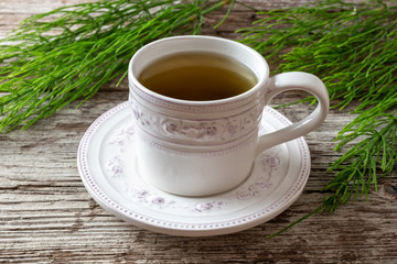 A cup of herbal tea with horsetail twigs