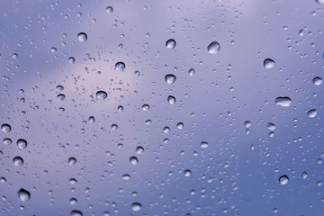 Rain drops with selective focus on transparent glass. Glass surface with water drops, violet toned. Window with raindrops. water drops on glass