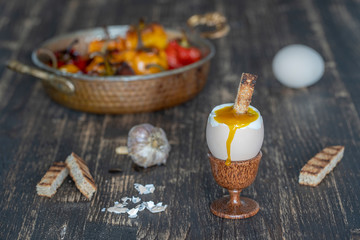 Fototapeta na wymiar Soft boiled egg in eggcup with slice of toasted bread on wooden table background, closeup