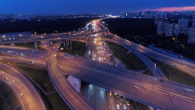Night multi-level great road junction overpass highway intersection difficult active traffic cars freeway. Beautiful cityscape old modern buildings Moscow Russia capital. Aerial forward above