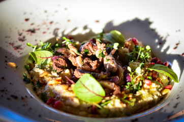 lebanese hummus dish with fresh vegetables, beef meat & pomegranate seeds