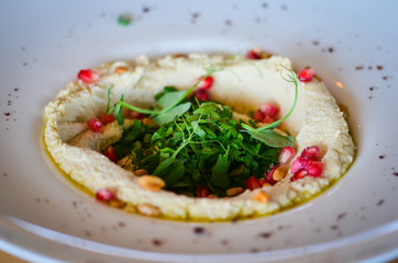 lebanese hummus dish with fresh vegetables, beef meat & pomegranate seeds