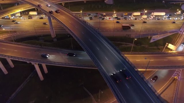 Close details multi-level night road junction backlit. Busy traffic jam.  Typical Moscow metropolis capital traffic. Way home logistics transport R ussia Europe. Aerial together with cars