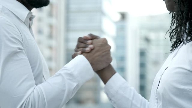 Slow motion shot of people shaking hands on street. Bearded man and woman with dreadlocks meeting on street and talking. Handshake concept