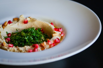 lebanese hummus dish with fresh vegetables, beef meat & pomegranate seeds