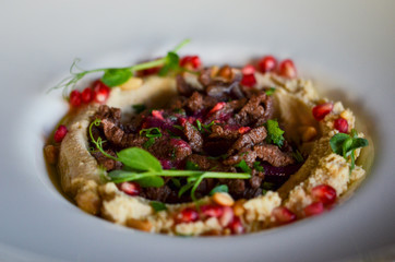 lebanese hummus dish with fresh vegetables, beef meat & pomegranate seeds