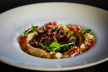 lebanese hummus dish with fresh vegetables, beef meat & pomegranate seeds