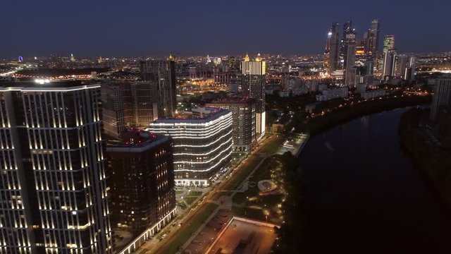 Night Moscow city illumination general plan cityscape skyscrapers cinematic updated modern district steel glass constructions. Dark river. Road traffic. Travel landmark. Aerial from great height 