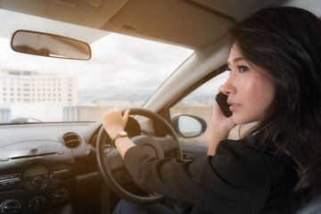 Beautiful Asian woman wear black suit work clothes. Talking on a mobile phone while driving
