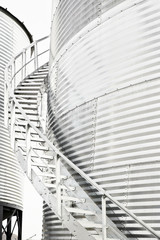 A stainless steel staircase wrapping around the outside of a steel grain storage agricultural bin © kat7213