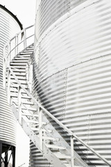 A stainless steel staircase wrapping around the outside of a steel grain storage agricultural bin