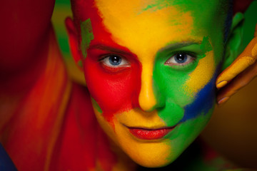 Portrait of the bright beautiful young woman with face art and body art. Contrast colors in creative make-up