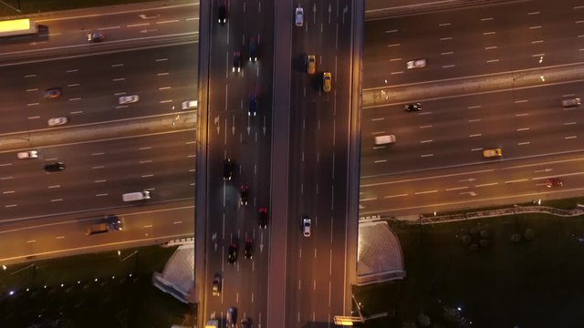 Night aerial top down speedy multi-lane wide cross road multi-level quiet road junction busy night traffic different transport ride lower and upper levels of road. Cinematic following 