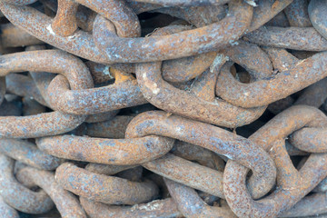 Stacked rusty iron chain as background.