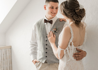 bride in white dress and groom in suit, posing in white Studio