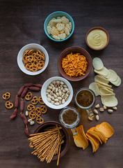 Oktoberfest beer with pretzels and various kinds of savory snacks. Beer snacks. Wood background. View from above. Place for text.