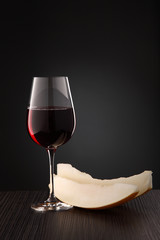 glass of red dry wine on a table with slices of melon and walnuts