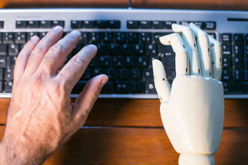 real and prosthetic hand typing on a computer keyboard