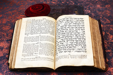 Jewish Bible. An open old Jewish book and a red knitted jewish bale. Torah in Hebrew and Aramaic...