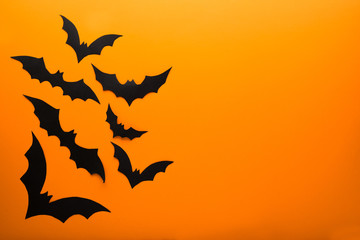 Halloween and decoration concept - black paper bats flying over orange background. Copy space.