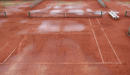 wet clay tennis court with puddles after the rain. Match canceled.. Season  is over.