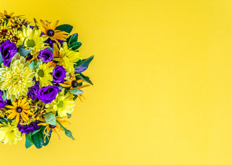 Stylish colorful beautiful spring bouquet isolated on light yellow background. Bright fresh purple and yellow flowers. Decorative composition greeting card for the holiday on the birthday. Copy space